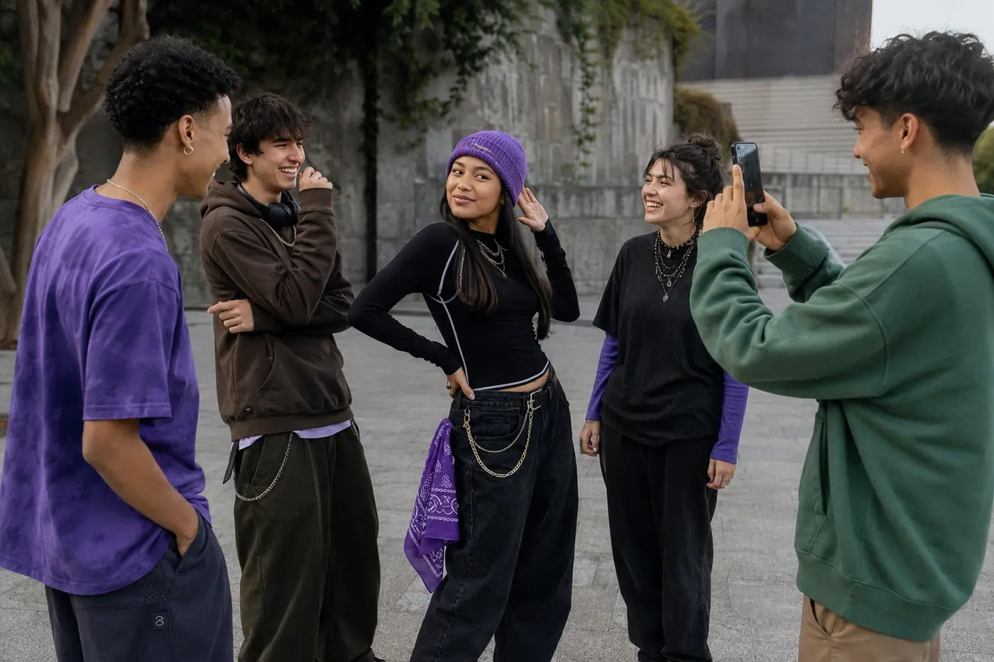 Grupo de jóvenes conversa y prepara una pose mientras uno de ellos sostiene un teléfono para grabar